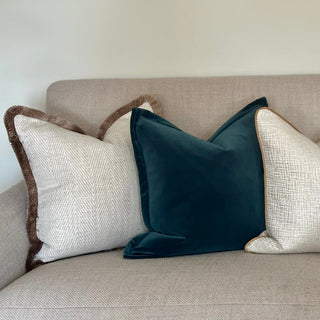 Decorative pillows on a beige sofa against a plain wall