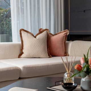 Decorative pillows on a beige sofa with a vase of flowers on a coffee table.