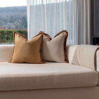 Beige sofa with decorative pillows in a room with large windows showing a scenic view.