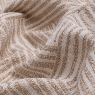 A close-up of a textured knit fabric with a wavy stripe pattern in beige and off-white.